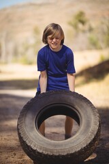 Wall Mural - determined girl exercising with huge tire during obstacle course