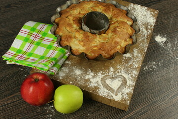 Homemade apple pie with a knitted cloth on wooden table