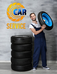 Wall Mural - Young mechanic in uniform with wheels, on gray background