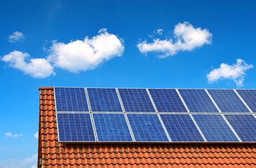 Wall Mural - solar panel on the roof of the house in the background blue sky.