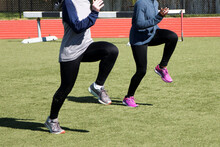 Two Girls Doing A-Skips Sprint Drills On A Turf Field