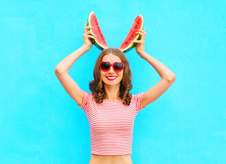 Happy pretty smiling woman is holding slice of watermelon over a colorful blue background