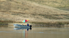Man Fishing On Lake With Multi-colored Umbrella