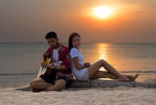 Cute Hispanic Couple Playing Guitar Serenading On Beach In Love And Embrace, Sunset In The Beach