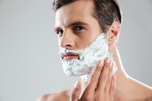 Concentrated Man Standing Isolated With Shaving Foam On Face