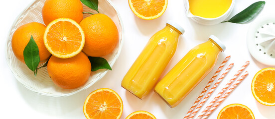 Two glass bottles of fresh orange juice, straws and oranges isolated on white background top view.