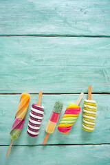 Sticker - colorful popsicle ice cream on turquoise wooden background