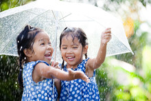 Two Happy Asian Little Girls With Umbrella Having Fun To Play With The Rain Together