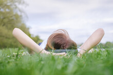 Caucasian Girl Lies On Green Grass In Park And Listens To Music