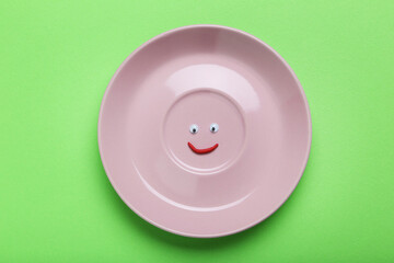 Wall Mural - Pink plate with googly eyes on a green background