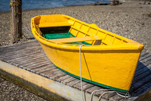 Bright Yellow Rowboat On Floating Dock On Beach