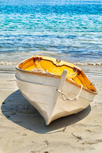 Wooden Rowboat Pulled Up Onto A Sandy Beach With The Water In The Background. Close Up 