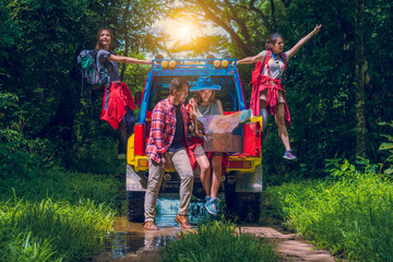 Happy asian young travellers with 4WD drive car off road in forest, young couple looking for directions on the map and another two are enjoying on 4WD drive car.