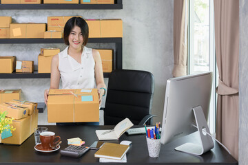 Portrait cute asian woman entrepreneur showing the box, teenager business owner work at home, many stuff to do today in home. Start up SME concept.