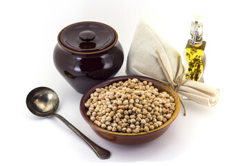 The composition of chick peas in a clay pial next to a clay pot and a copper spoon,