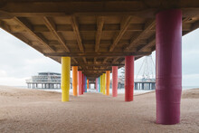 Shot Under Pier With Color Painted Columns On The Beach At Sunset.