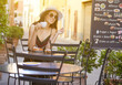 © ZoomTeam - Young woman having italian breakfast with croissant and coffee at the cafe on the street