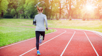 Wall Mural - Athletic woman running on track back view, healthy lifestyle