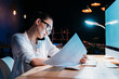 © LIGHTFIELD STUDIOS - Young asian businesswoman in eyeglasses holding blueprint and talking on smartphone