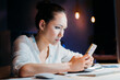 © LIGHTFIELD STUDIOS - concentrated asian businesswoman using smartphone, working late at the office