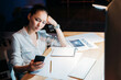 © LIGHTFIELD STUDIOS - young tired asian businesswoman holding eyeglasses and using smartphone, working late at the office