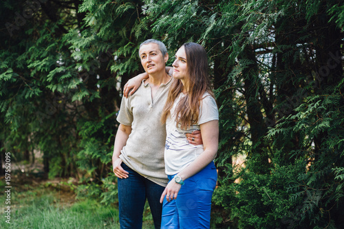 Fotografia Smiling middle-aged mother and adult daughter in law hugging before the green trees in yard