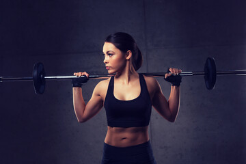 Poster - young woman flexing muscles with barbell in gym