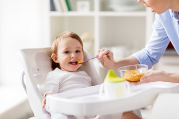 Wall Mural - happy mother feeding baby with puree at home