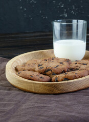 Chocolate chip cookies on dark background with glass of milk