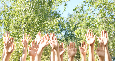 Canvas Print - Young people putting hands in air together outdoors. Volunteering concept