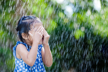 Wall Mural - Happy asian little girl having fun to play with the rain