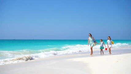 Wall Mural - Family of mother and kids walking on white beach