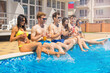 © Igor Kardasov - Party at smimming pool. Group of cheerful friends drinking cocktails and beer sitting on the edge of the pool. They look happy