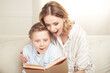 © LIGHTFIELD STUDIOS - Excited mother and son sitting embracing and reading book together