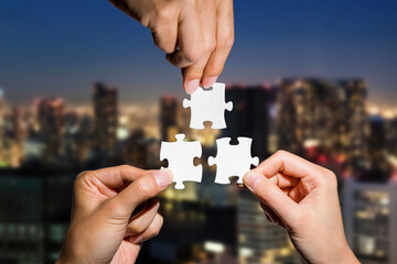 three hands holding piece of jigsaw puzzle on cityscape background. business partnership concept. bu