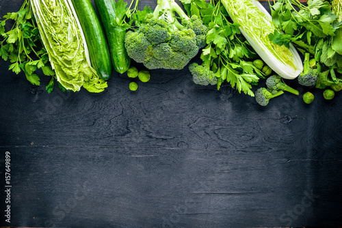 Stampe Collection of fresh green vegetables placed on black stone