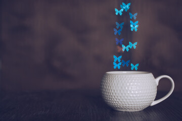 Wall Mural - A cup of coffee on a wooden table and bokeh butterfly.