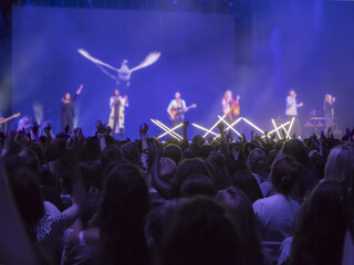 Silhouette of people with hands raised worshiping to the God in concert.