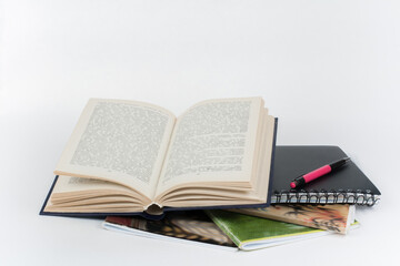 Wall Mural - Open book, colorful notebook, pen on white table.