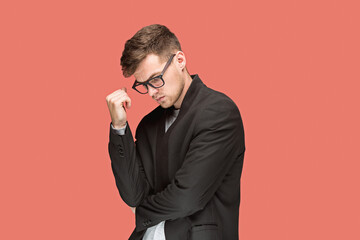 Wall Mural - Young handsome man in black suit and glasses isolated on red background