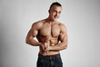 © Stasique - Smiling male athlete with naked muscular torso posing in studio over grey background.