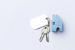 Blue miniature house with key on white background, property and real estate concept