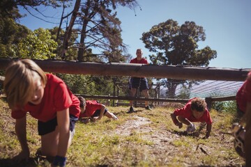 Wall Mural - kids crawling under the net during obstacle course training