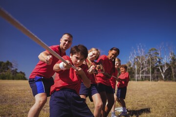 Wall Mural - trainer assisting kids in tug of war during obstacle