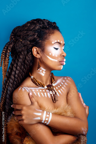 Plakat African style woman . Attractive young woman in ethnic jewelry . close up portrait of a woman with a painted face. Creative makeup and bright style.