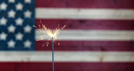 Glowing sparkler with rustic wooden flag of United States of America for independence, labor, July 4th, president, veteran and Memorial day holiday celebration background