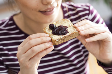 Young woman eating toast bread with jam