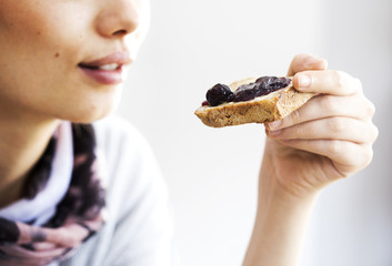 Young woman eating toast bread with jam