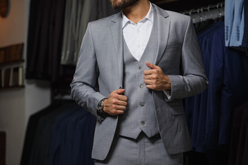 Wall Mural - Modern young handsome businessman looking and choosing classical suit in the suit shop