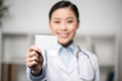 © LIGHTFIELD STUDIOS - selective focus of smiling doctor showing blank card in hand